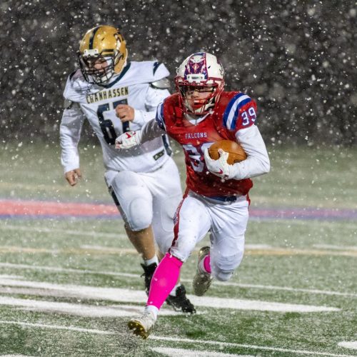 High school football running back advances the ball in a snow storm