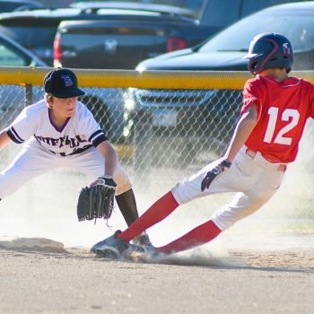 boys youth baseball player slides into third base